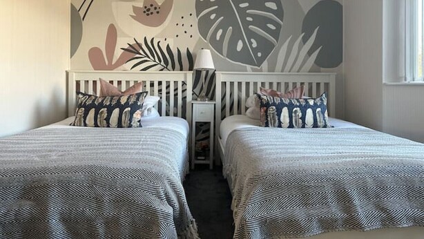 A room with two beds, a nightstand, a lamp, and a wall mural. - The Bungalow Birmingham NEC Airport Bullring (Birmingham)