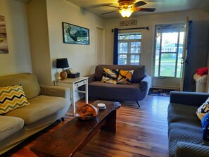 A living room with a ceiling fan, a couch, a coffee table, and a window with blinds. - SHADY DECK LODGE, TURKEY POINT, July & August min 7 days SAT. to SAT. $2000.00+ (Vittoria)