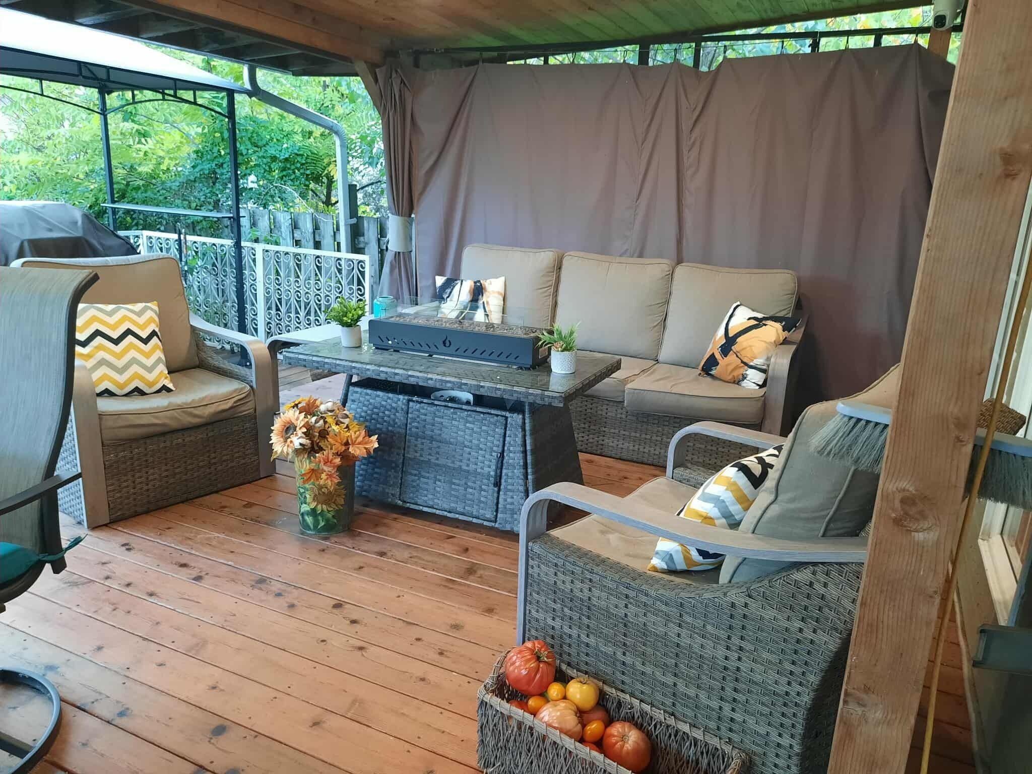 Un espace extérieur aménagé avec des meubles en osier, une table et un pot de fleurs.