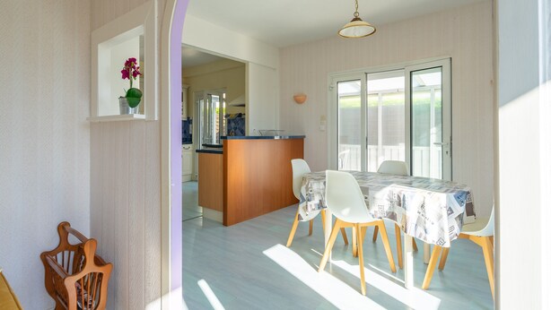 A dining area with a table, chairs, and a kitchen in the background. - Holiday Home “Quartier Calme” with Private Garden (Royan)