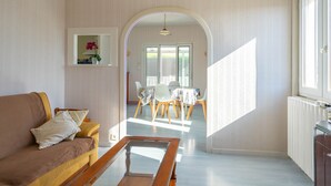 A living room with a sofa, a coffee table, and a dining area with chairs and a table. - Holiday Home “Quartier Calme” with Private Garden (Royan)