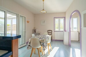 Een eethoek met een tafel, stoelen en uitzicht op buiten.