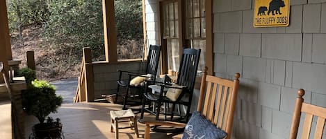 A covered porch with wooden chairs and a 'DO NOT PET THE FLUFFY DOGS' sign.