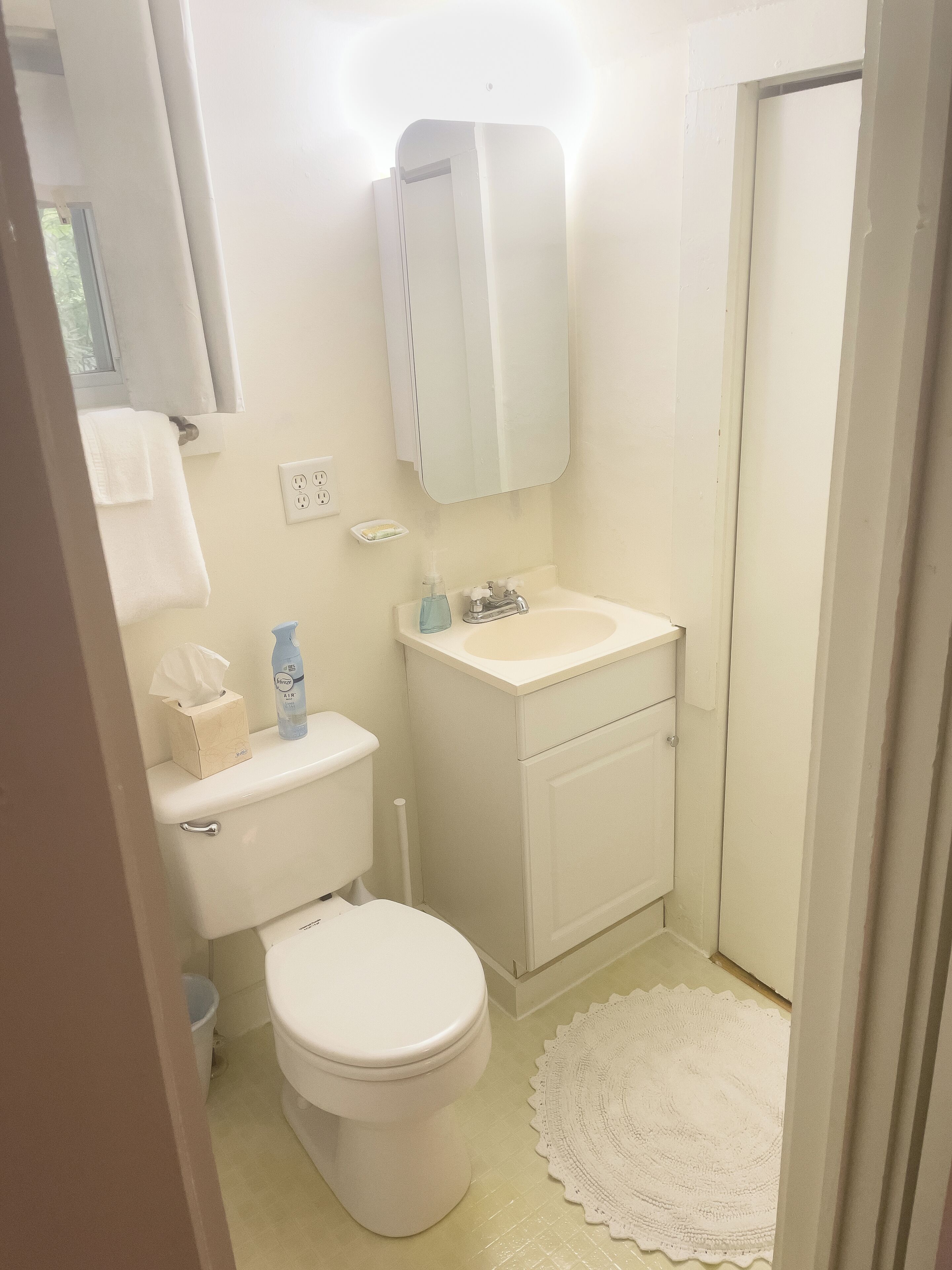 Une petite salle de bain propre, équipée de toilettes, d’un lavabo et d’un miroir.