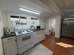 A kitchen with white cabinets, a stainless steel refrigerator, a microwave, and a stove. - Great house and a porch full of rocking chairs in Montreat close to Lake Susan (Montreat)
