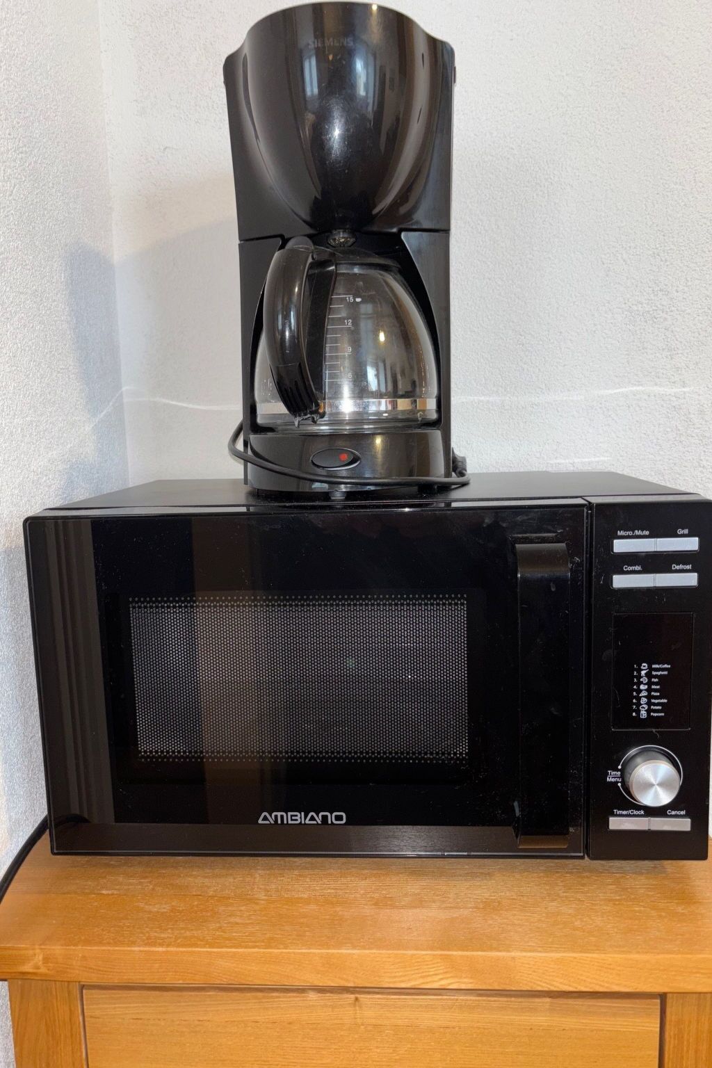 A black coffee maker on a wooden cabinet.