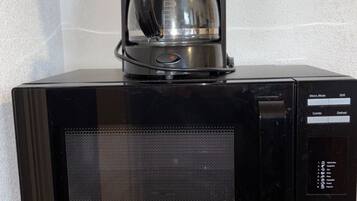 A black coffee maker on a wooden cabinet.