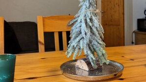 A dining table with a small artificial Christmas tree centerpiece, a wooden chair, and a painting on the wall. - 2_9 Cosy Kaprun Apartment by Interhome (Kaprun)