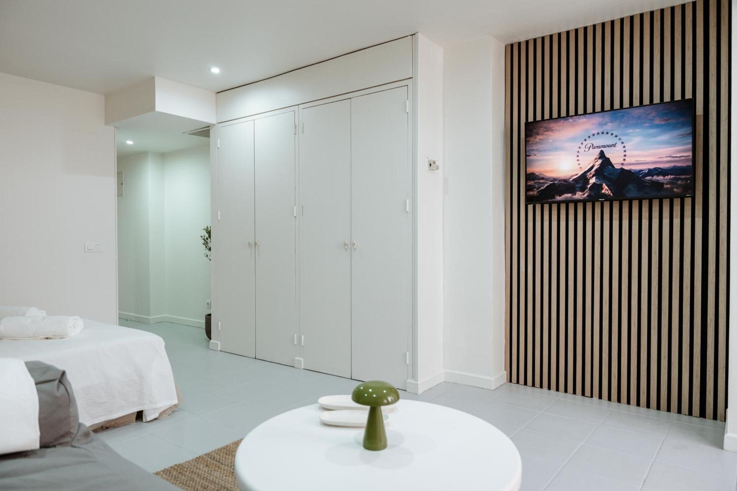 A bedroom with a bed, a wardrobe, a TV, and a decorative item on a table.