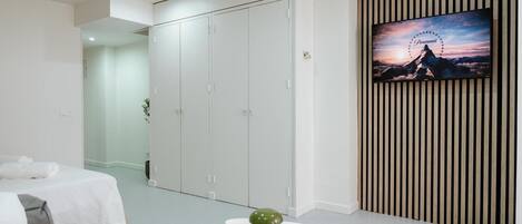 A bedroom with a bed, a wardrobe, a TV, and a decorative item on a table.