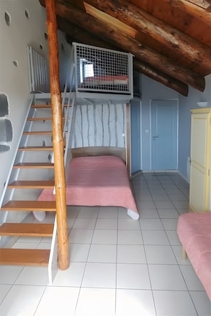 A room with a bunk bed, a staircase, a radiator, and a wardrobe.