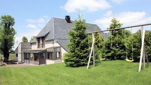 A house with a large porch, a swing set, and a covered outdoor seating area.