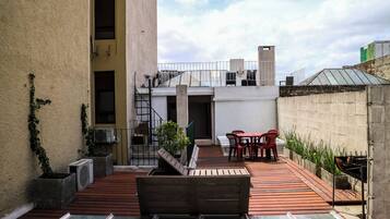 A rooftop terrace with a pool, outdoor seating, and a grill.