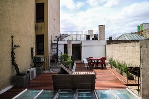 Une terrasse sur le toit avec une piscine, des espaces salons extérieurs et un barbecue.