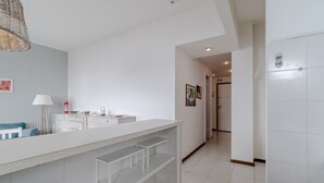 Un bany modern amb un lavabo blanc, una làmpada penjant i un terra amb rajoles.