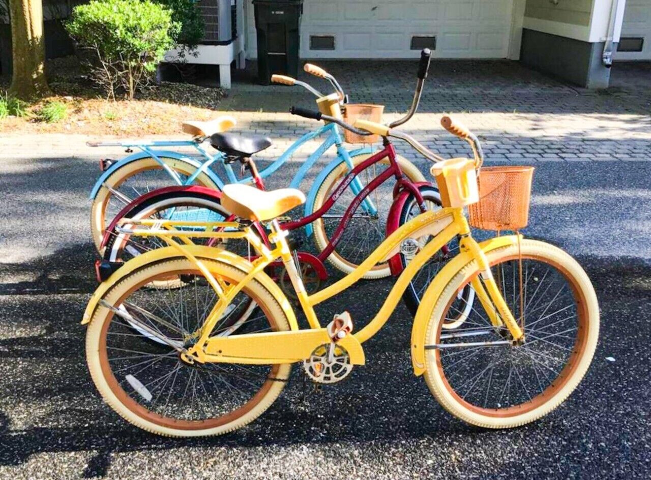 Een gele fiets met een mandje en zitting, geparkeerd op een verhard oppervlak.