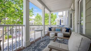 A covered porch with a sofa, two side tables, and a patterned rug.