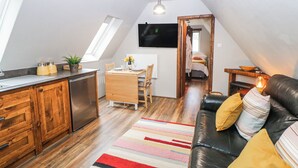A compact living space with a kitchenette, dining area, and a cozy seating area with a sofa and cushions. - Little Mill (Chesterfield)