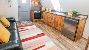 A compact kitchen with wooden cabinets, a built-in oven, and a stainless steel refrigerator. - Little Mill (Chesterfield)