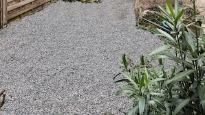 Ein Kieshof mit Holzzaun, einem Blumentopf und einer Steinmauer.