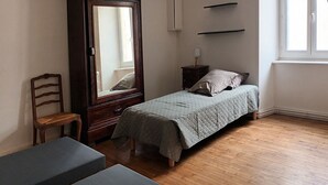 Ein Schlafzimmer mit Bett, Stuhl, Kommode und Fenster.