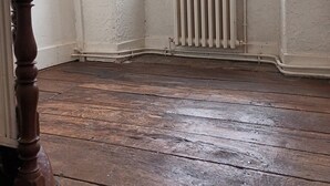 Ein Zimmer mit Holzboden, Heizkörper und Fenster.
