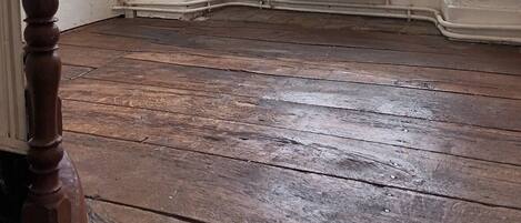 A room with a wooden floor, a radiator, and a window.