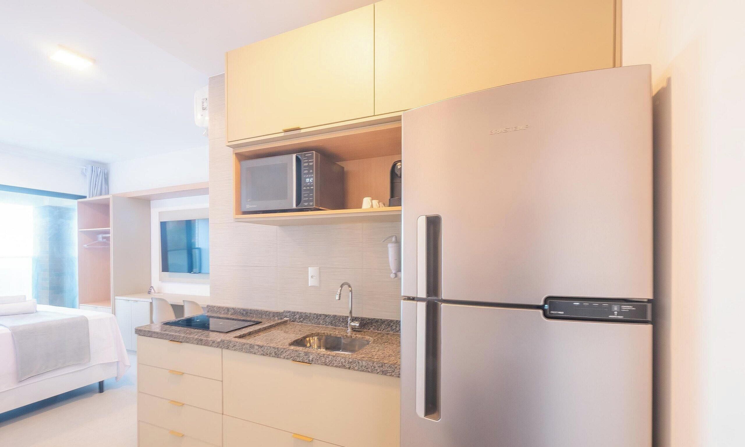 A modern kitchen with a built-in microwave, a stainless steel refrigerator, and a granite countertop.