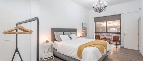 A bedroom with a bed, bedside table, lamp, and a view of the outdoors.