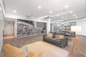 Uma sala de estar moderna com um sofá, uma mesa de centro, um abajur e uma estante de livros.
