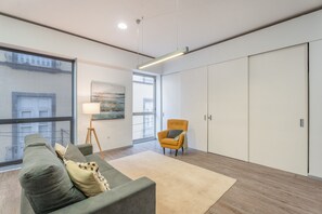 Uma sala de estar moderna com sofá, poltrona e uma janela grande.