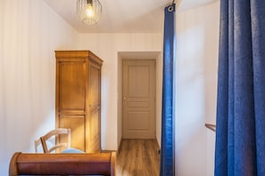 A room with a wooden cabinet, a chair, a door, and a blue curtain. - Ségonzac Cottage: Lake View, Private Terrace, Wi-Fi (Villecomtal)