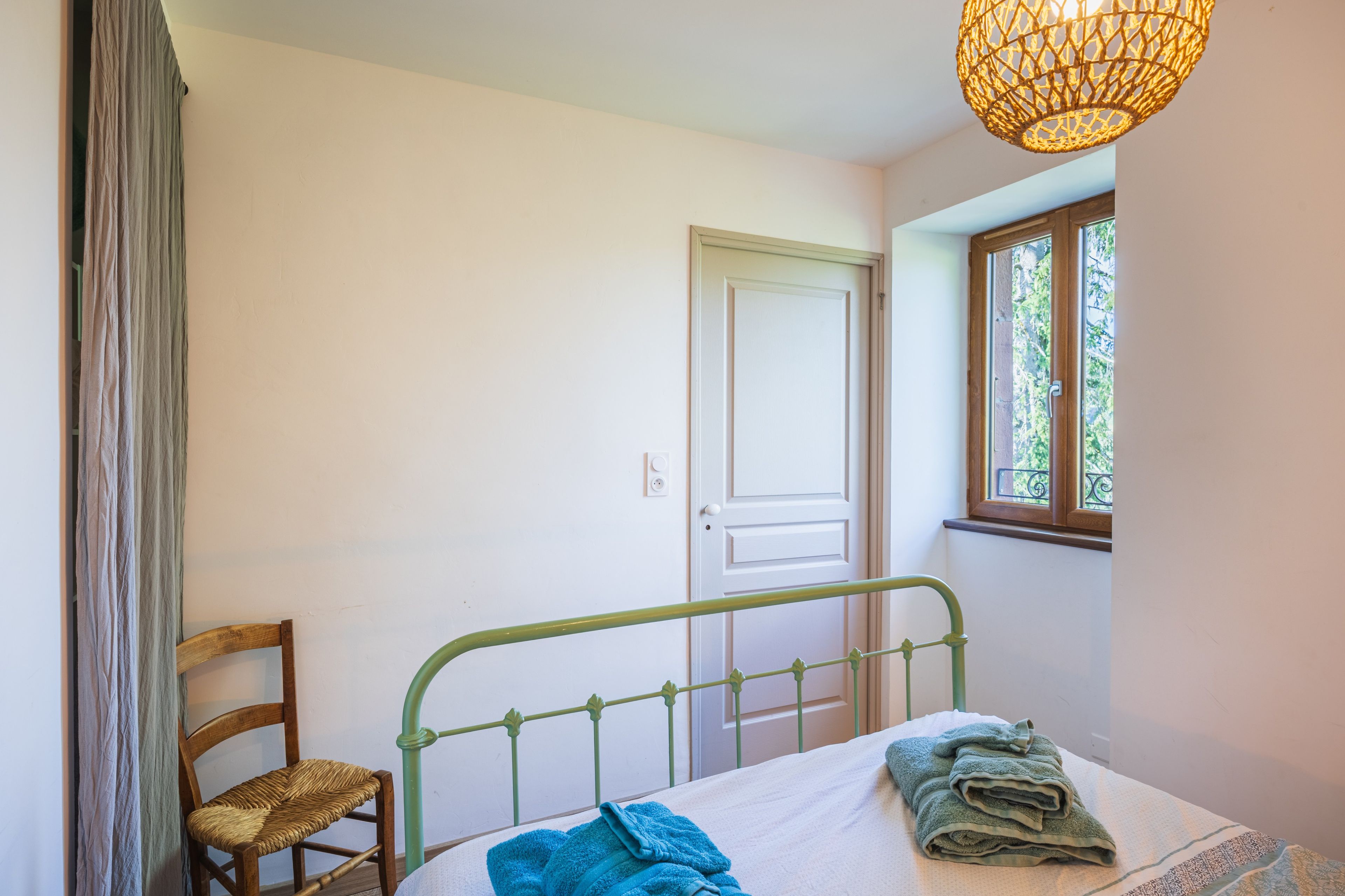 Un dormitorio con una cama, una silla, una puerta y una ventana.