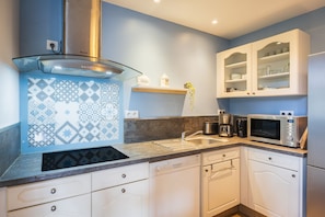 A modern kitchen with a dishwasher, microwave, and a coffee maker. - Ségonzac Cottage: Lake View, Private Terrace, Wi-Fi (Villecomtal)