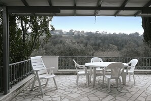 A covered outdoor seating area with a stone floor, white plastic chairs, and a table. - N316 - Numana, comfortable three-room apartment with large terrace (Numana)