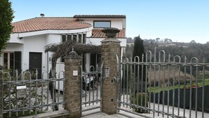 Una proprietà recintata con un ingresso in pietra, un tetto in tegole e vista su un paesaggio rigoglioso.