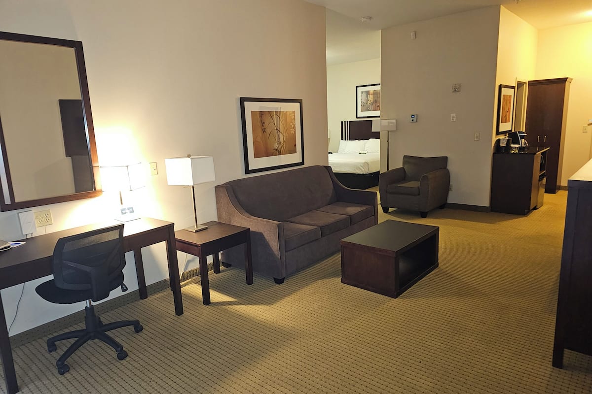 Quarto de hotel com escrivaninha, cadeira de escritório, sofá, poltrona e uma mesinha.