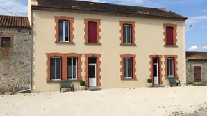 Un bâtiment à deux étages, doté de nombreuses fenêtres et portes, avec un sol pavé et un ciel dégagé.
