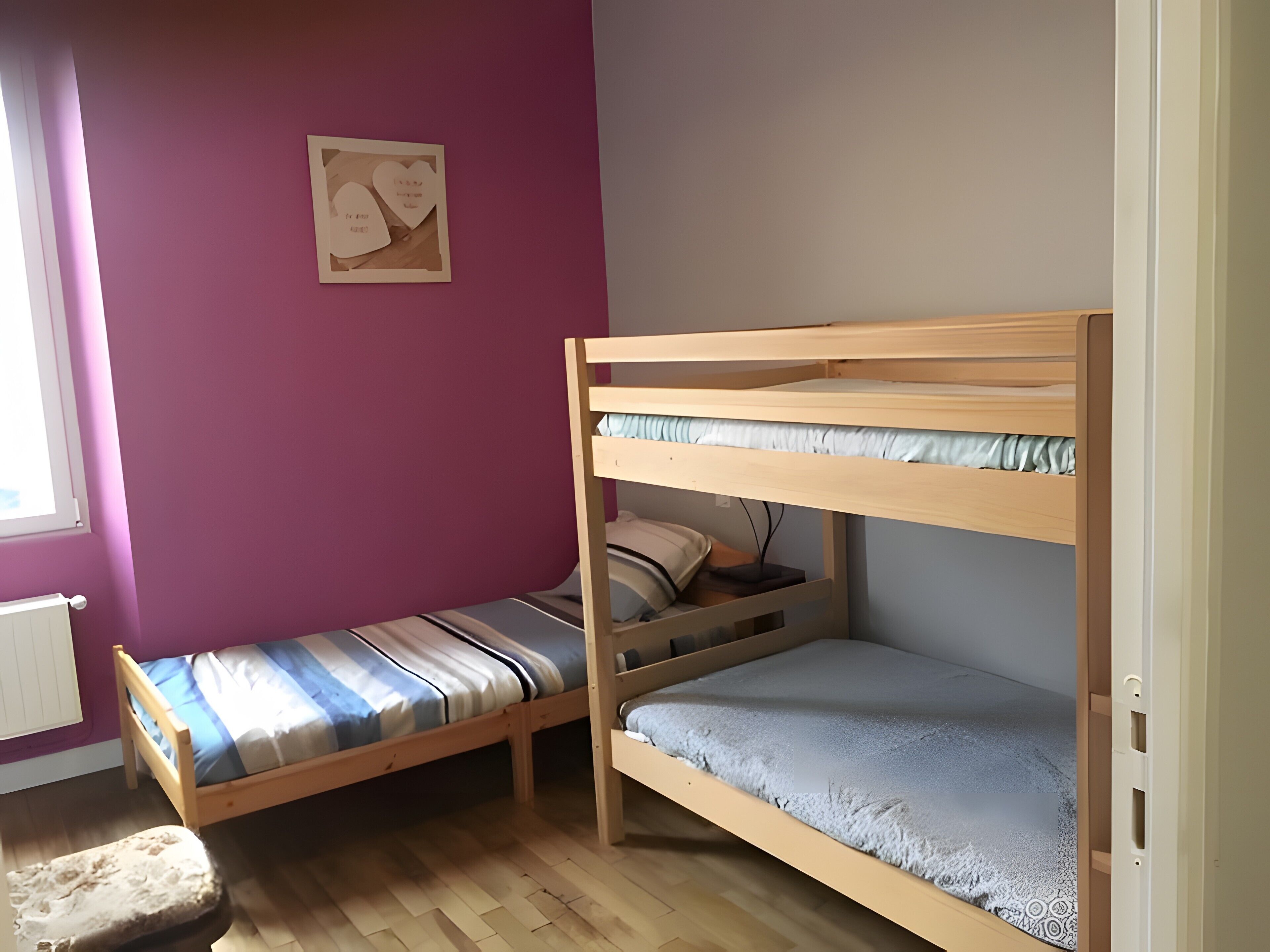 Quarto com beliche, janela, radiador e um adorno na parede.