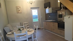 Une cuisine moderne avec un coin repas, comprenant une table ronde, des chaises blanches et une vue sur l’extérieur.