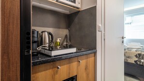 Una kitchenette compacta equipada con microondas, cafetera y lavamanos.