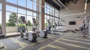 Un gimnasio con cintas de correr, elípticas y equipo de pesas.