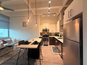 A modern kitchen with stainless steel appliances, a dining area with a table and chairs, and a living area with a sofa and a window. - Luxury Cozy 1-bedroom apartment gorgeous Atlanta (Atlanta)