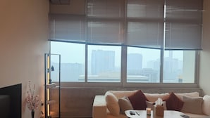 Una sala de estar moderna con un sofá, una mesa de centro, un televisor y un ventanal con persianas.