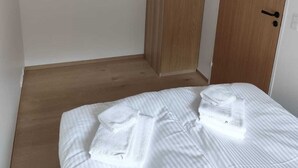 A bedroom with a bed, a wooden wardrobe, and a door. - Sea View Apartment with balcony 2BR (Argir)