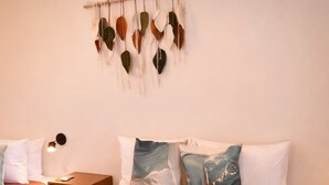 Une chambre d’hôtel avec deux lits, une œuvre d’art accrochée au mur, une table de chevet avec une lampe et une petite table de nuit.