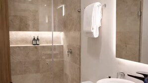 Une salle de bain moderne avec une douche à parois de verre, un lavabo blanc et un meuble-lavabo en bois.