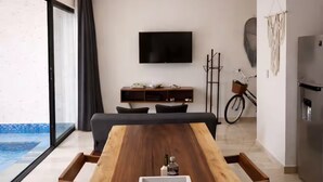 Un salon moderne avec une table à manger en bois, un téléviseur fixé au mur et un vélo en arrière-plan.