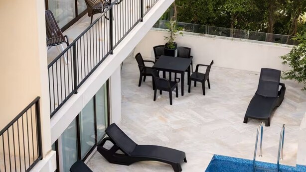 Un espace piscine aménagé sur le toit, avec des chaises longues, une table et des chaises.