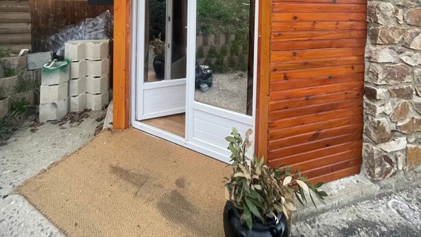 Un edificio con fachada de madera, una pared de piedra y un acceso por puerta de cristal.
